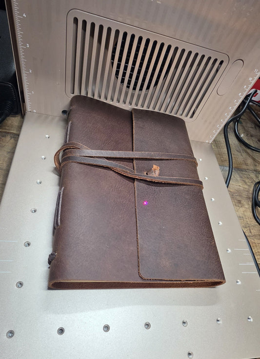 A brown leather journal being engraved.