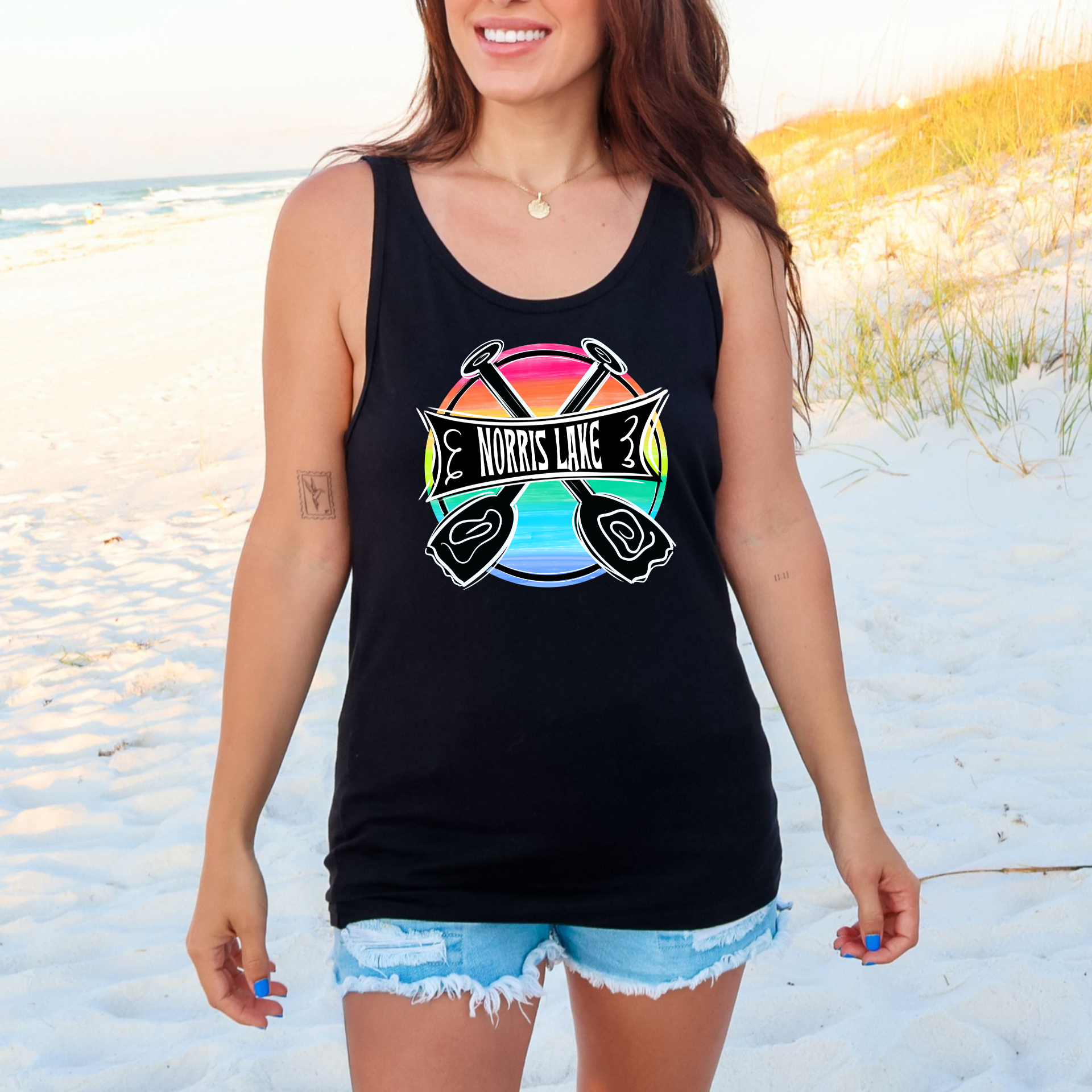 Woman wearing a black tank top with a colorful graphic on a beach