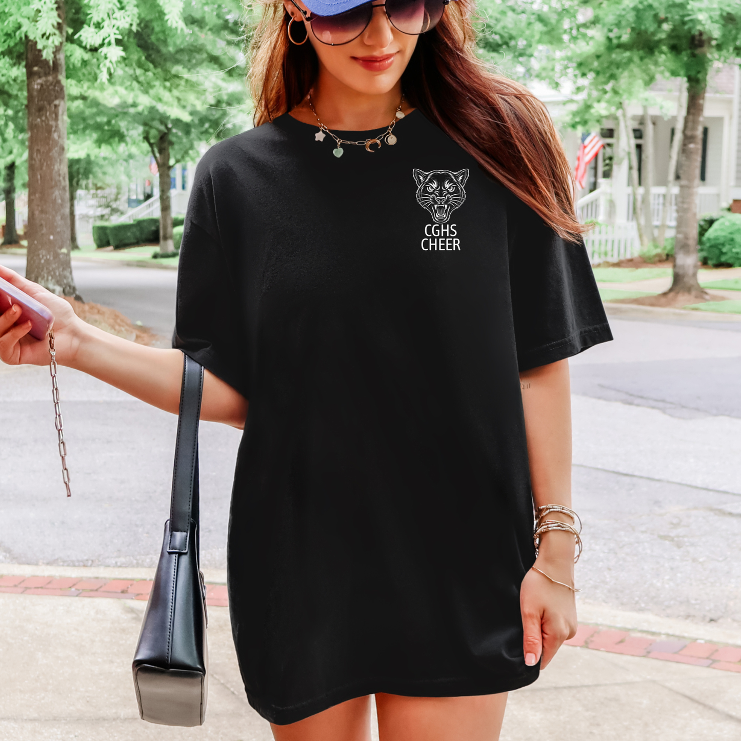 A woman wearing an oversized black t-shirt dress with a white graphic of a tiger face and the text 'EGGS CHEER' on the left chest, standing outdoors on a sidewalk.