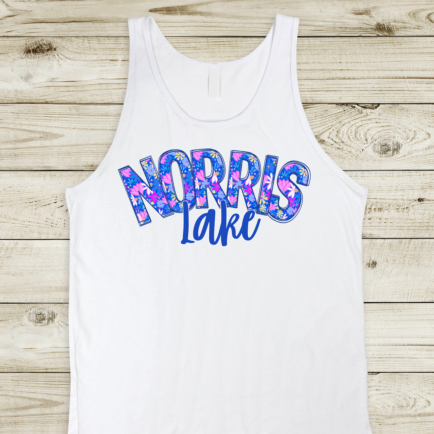 White tank top with 'NORRIS LAKE' printed in colorful letters on a wooden surface
